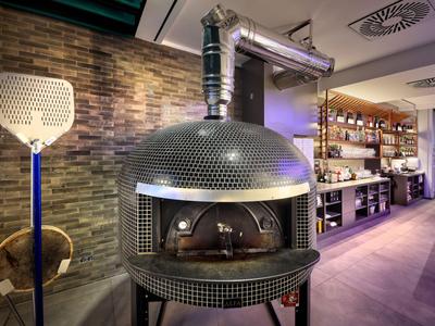 Four à pizza moderne dans une salle à manger élégante avec mur en pierre et sièges rembourrés.