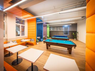 Salon moderne avec table de billard, murs colorés et espaces de détente confortables dans un hôtel.