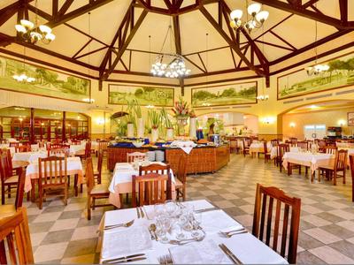 Großes Restaurant mit Holzmobiliar, gelben Wänden und gemustertem Boden in Hotelambiente.