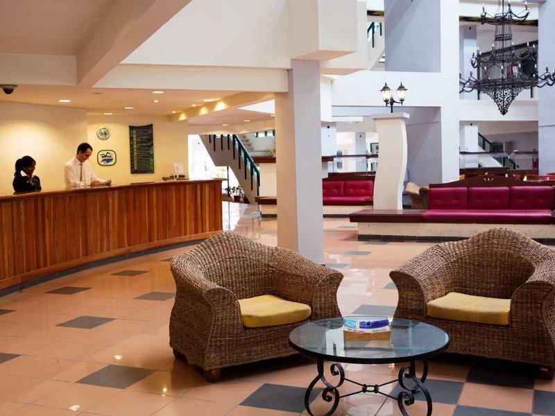 Helle Hotellobby mit Teppichmöbeln und Holzelementen, großzügiger Raum mit Treppe und Sitzbereichen.