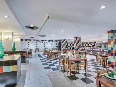 Moderner Restaurantraum mit bunten Fliesen, Holztischen und gedeckten Plätzen in hellem Ambiente.