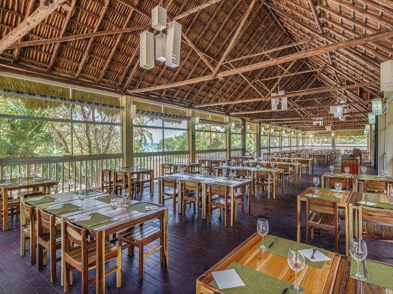 Großes Restaurant mit Holztischen, Stühlen und Dach aus Holzbalken, viel natürlichem Licht.