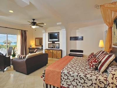 Helles Schlafzimmer mit gemustertem Bett, zwei Sofas und großer Glas-Schiebetür zum Balkon.