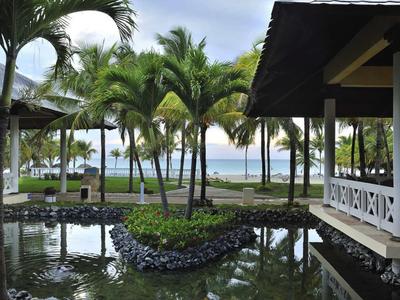 Tropische Hotelanlage mit Palmen, Wasserbecken und Blick auf das Meer.
