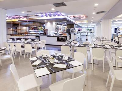 Helles, modernes Restaurant mit weißen Stühlen und eingedeckten Tischen.