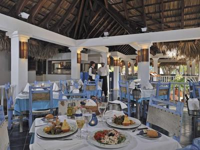Restaurant mit gedeckten Tischen und Blick auf das Meer, rustikales Dach und entspannte Atmosphäre.