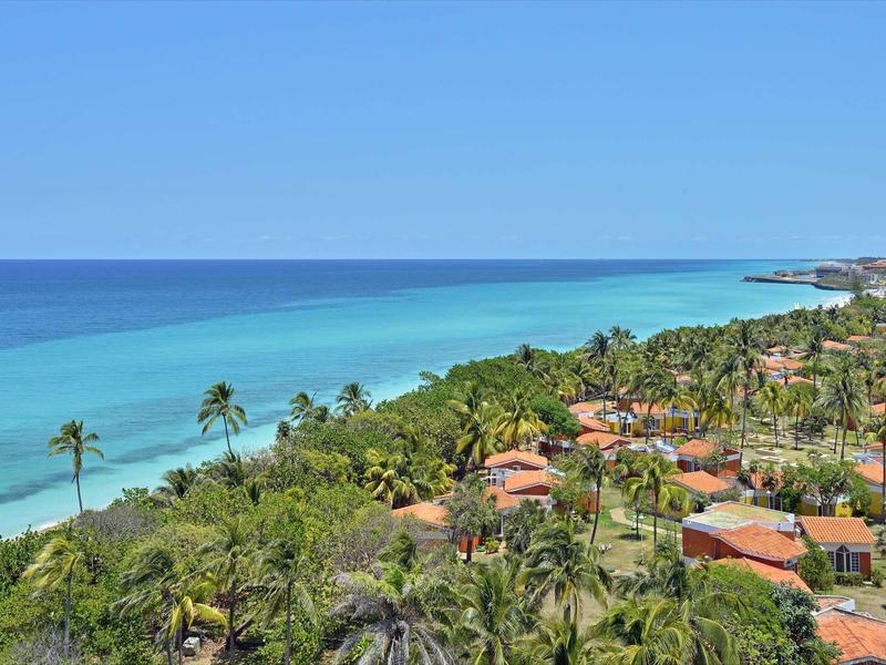 Blick auf eine Küste mit grüner Vegetation und blauer See unter klarem Himmel.