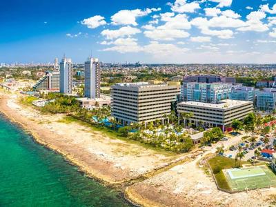 Breiter Strand mit Hotels und türkisfarbenem Meer unter blauem Himmel.