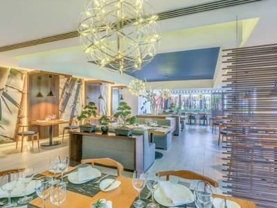 Elegantes Restaurant mit modernem Design, Tischen mit weißen Tischdecken und stilvoller Beleuchtung.