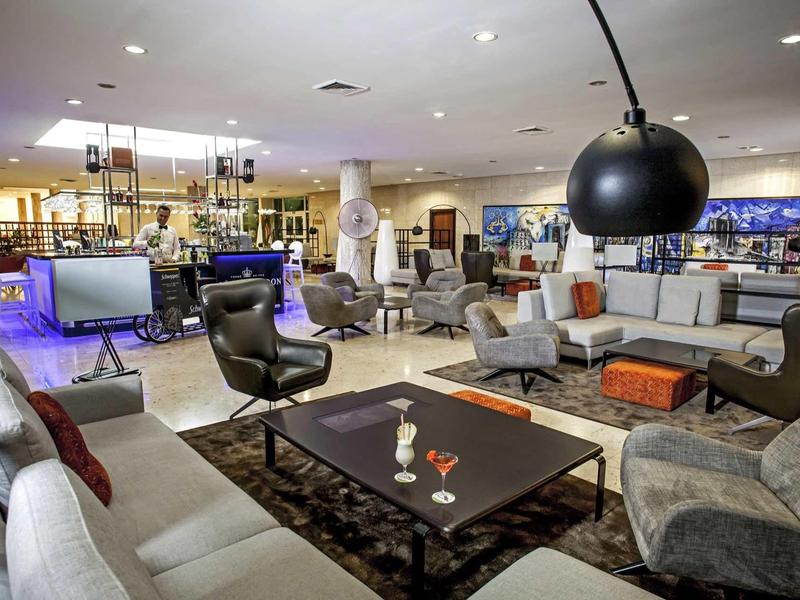 Großer, moderner Wohnraum mit Sofas, Sesseln, Couchtischen und großen Hängeleuchten in heller Atmosphäre.