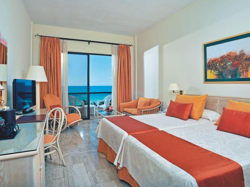 Hotelzimmer mit zwei Betten, Meerblick und moderner Einrichtung mit warmen Farben.