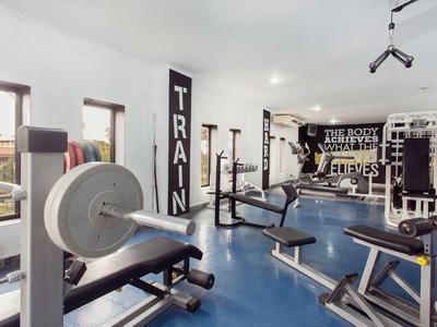 Heller Fitnessraum mit verschiedenen Trainingsgeräten und blauen Bodenbelag.