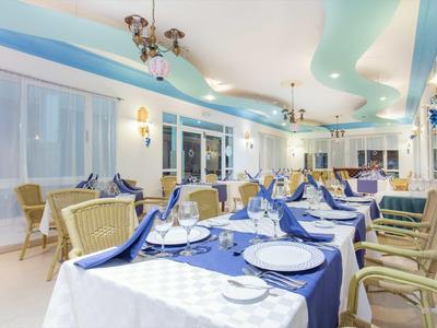 Eleganter Speisesaal mit blau-weiß gedeckten Tischen und bequemen Stühlen in heller, heller Atmosphäre.