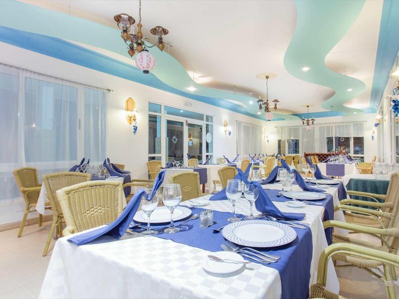 Eleganter Speisesaal mit blau-weiß gedeckten Tischen und bequemen Stühlen in heller, heller Atmosphäre.