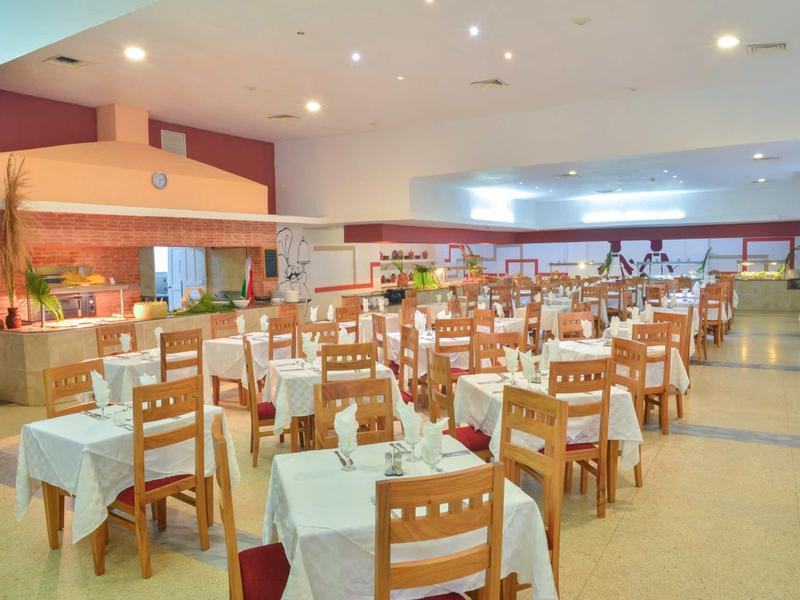 Großer, heller Speisesaal mit eingedeckten Tischen und Holzmöbeln in einem Hotel.