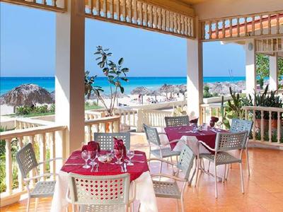 Terrazza di un ristorante con tavoli apparecchiati e vista sul mare sullo sfondo.