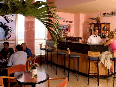 Hotel bar with wooden furniture and guests enjoying drinks in a cozy setting.