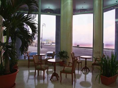 Seating area with chairs and tables by large windows overlooking water