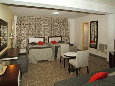 Hotel room with two single beds, seating area, desk, and carpeted floor.