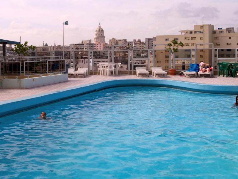 Large outdoor pool with clear water and cityscape in the background.
