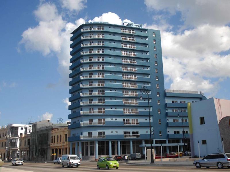Tall blue hotel building with multiple floors under a cloudy sky.