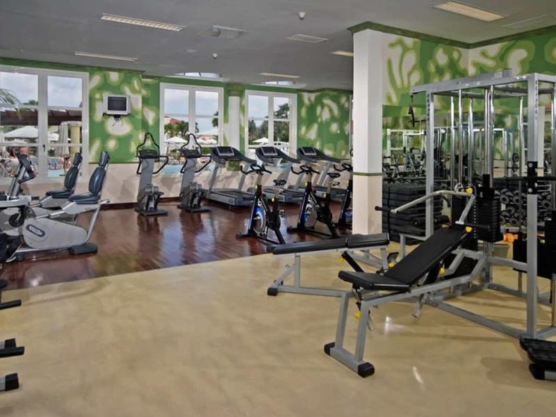 Palestra moderna con attrezzi e grandi finestre che illuminano l'ambiente.