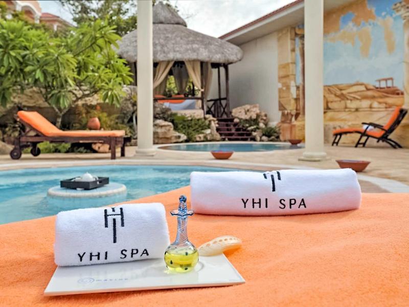 Asciugamani e accessori spa vicino a una piscina con lettini sullo sfondo.