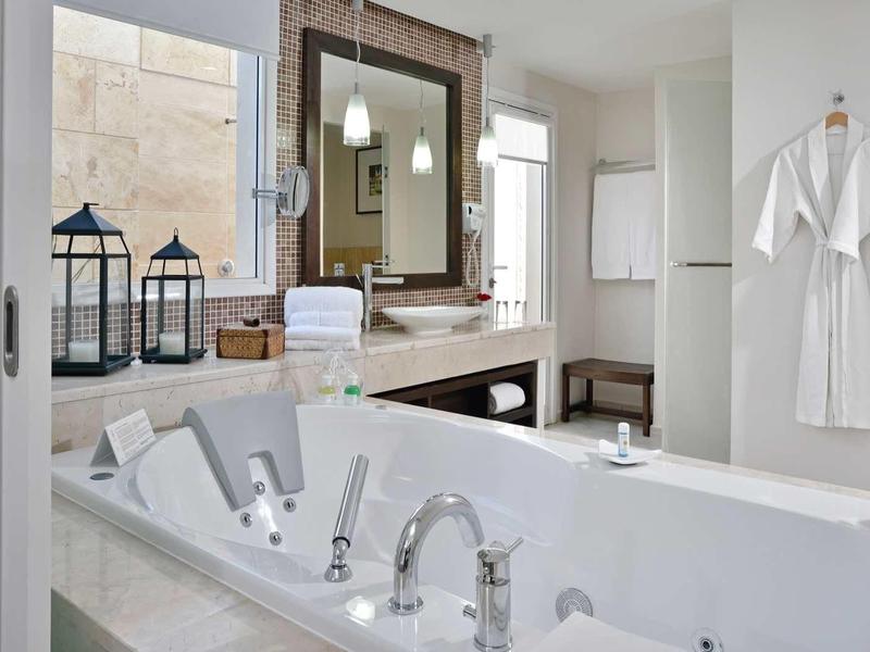 Bagno d'albergo luminoso con vasca moderna, accappatoi e decorazioni eleganti.