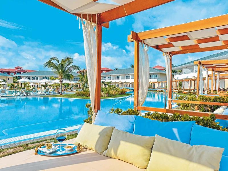 Piscina di lusso con divani comodi e pergolati in un resort tropicale.