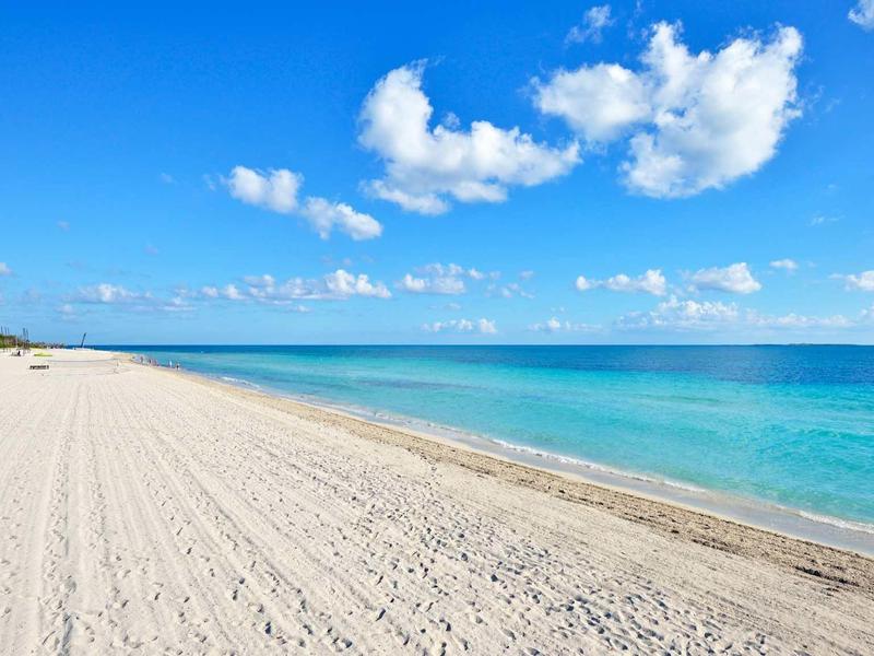 Spiaggia di sabbia bianca con mare turchese e cielo azzurro.