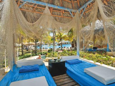 Chatka s modrými postelemi a dekorativní sítí u tropické pláže.