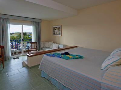 Jednoduchý hotelový pokoj s postelí, TV, terasou a výhledem do zahrady.