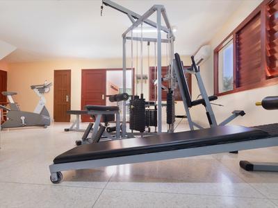 Moderní posilovna s různými tréninkovými stroji a velkými okny.