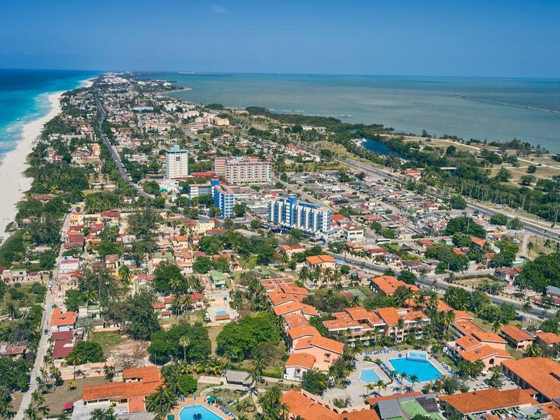 Vista aerea di una città costiera con hotel, spiagge e acqua limpida e blu.