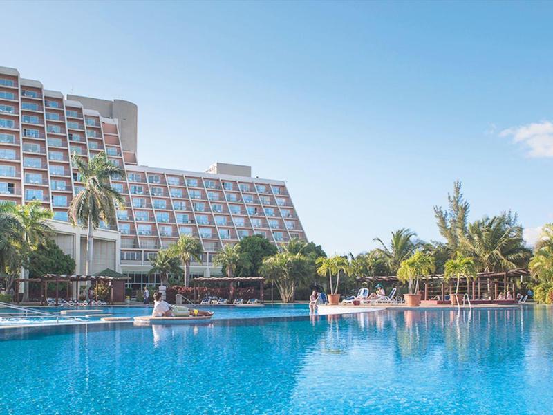 Hotel con grande piscina, palme e cielo sereno sullo sfondo