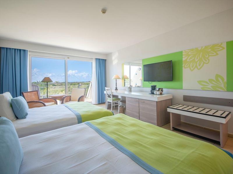 Camera d'hotel moderna con due letti, balcone e vista mare