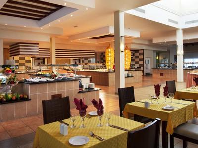Large hotel dining area with set tables and a diverse buffet under a bright skylight.