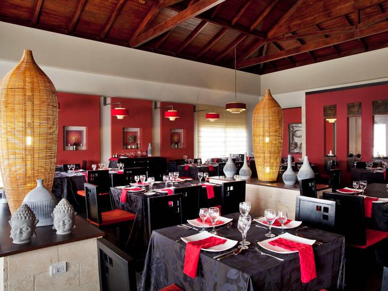 Elegant restaurant with black and red tablecloths and large wooden ceiling.