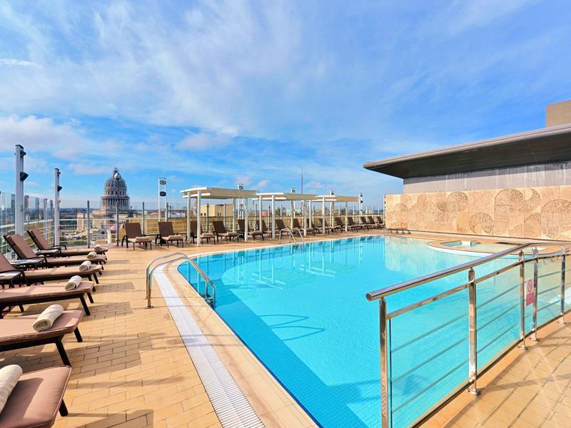 Modern buitenzwembad op het dak met ligstoelen en uitzicht op de lucht.