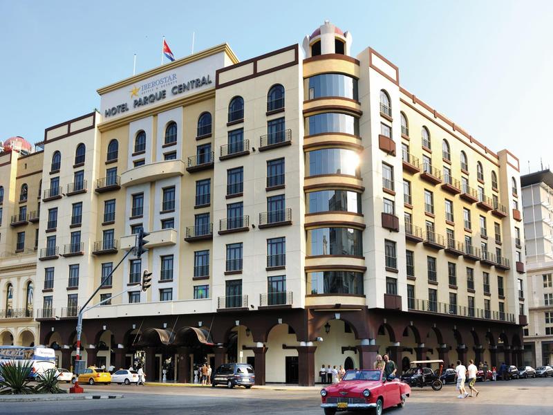 Groot traditioneel stadshotel met meerdere verdiepingen en veel balkons op een druk kruispunt.