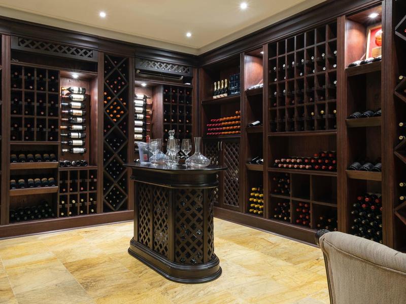 Wijnkelder met donkere houten planken met wijnflessen en een tafel in het midden.