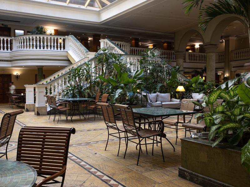 Grote lichte binnenruimte met gezellige zitplaatsen en veel planten in een hotel.