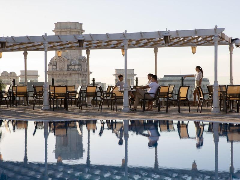 Terras met stoelen en tafels naast een zwembad bij zonsondergang