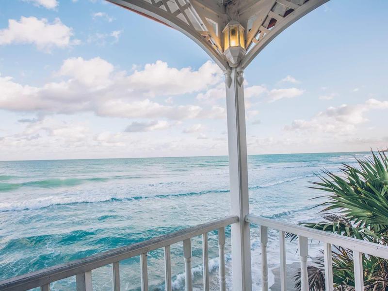 Vista da un balcone bianco con ringhiera su un cielo nuvoloso e il mare.