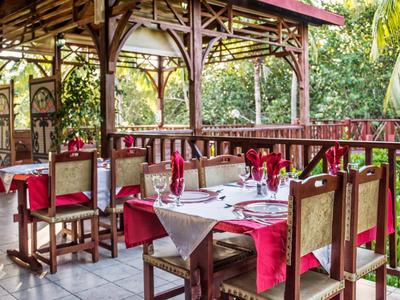 Ristorante all'aperto con mobili in legno e tavoli apparecchiati in un ambiente tropicale.