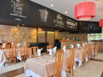 Ristorante luminoso con tavoli e sedie in legno e lavagna del menu sulla parete.