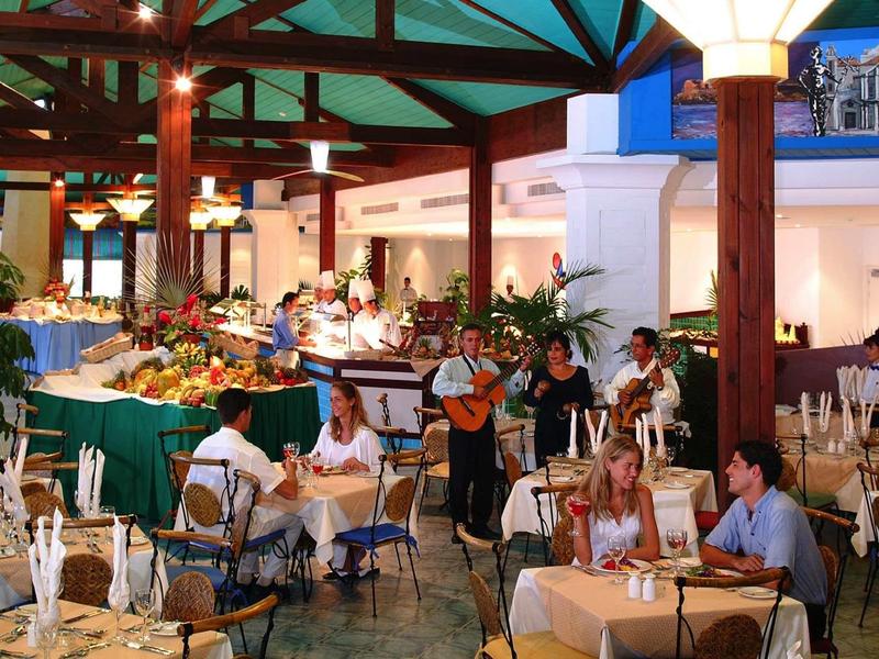 Terrazza di ristorante all'aperto con clienti e musica dal vivo sotto una struttura in legno.