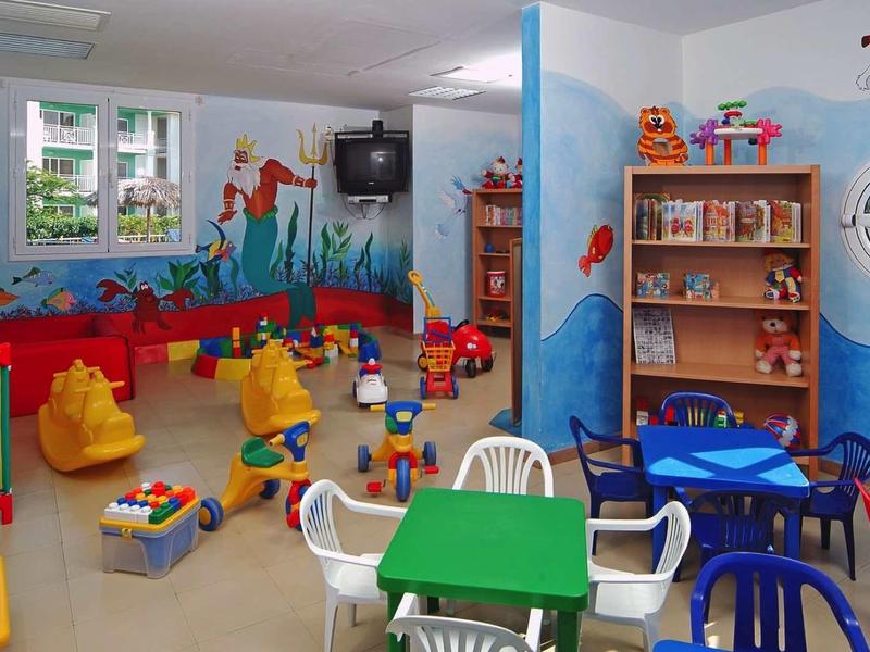 Sala giochi colorata con tavoli, sedie e giocattoli in un hotel per bambini.