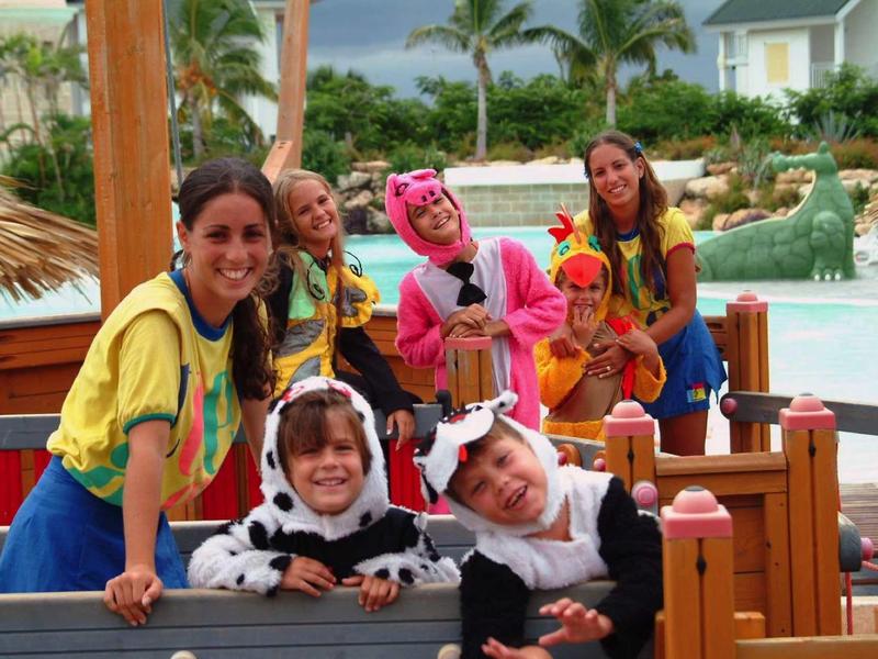 Gruppo di bambini in costume che si divertono su un'area giochi estiva vicino a una piscina.