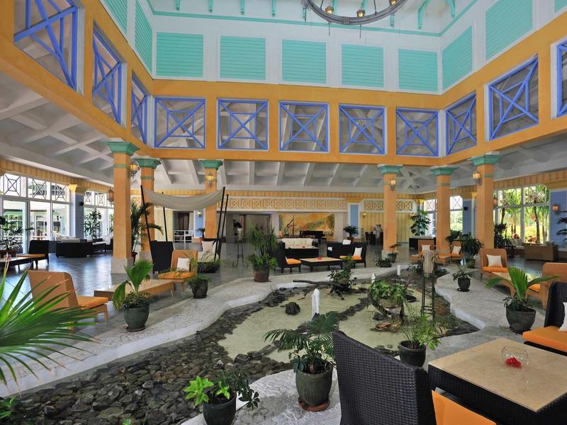 Ampia hall luminosa con piante, zone salotto confortevoli e grandi finestre.